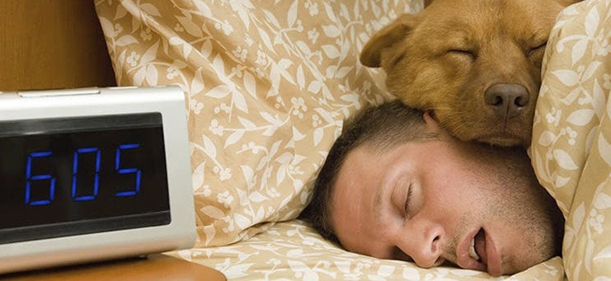 A man sleeping with his dog sleeping on his head