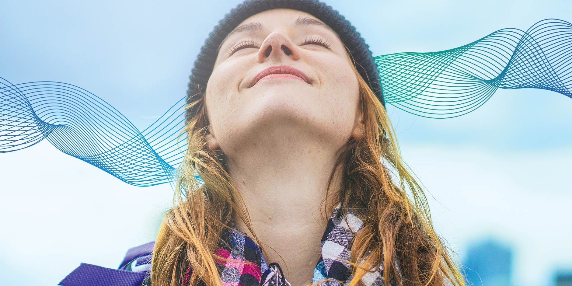 Nasenatmung: Frau mit Mütze und kariertem Schal atmet mit erhobenem Kopf frische Luft ein
