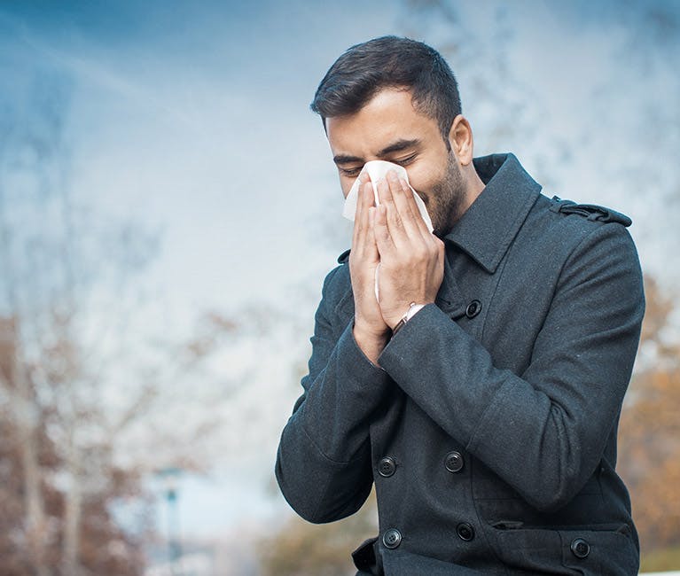 Woman dressed in winter clothing blowing her nose