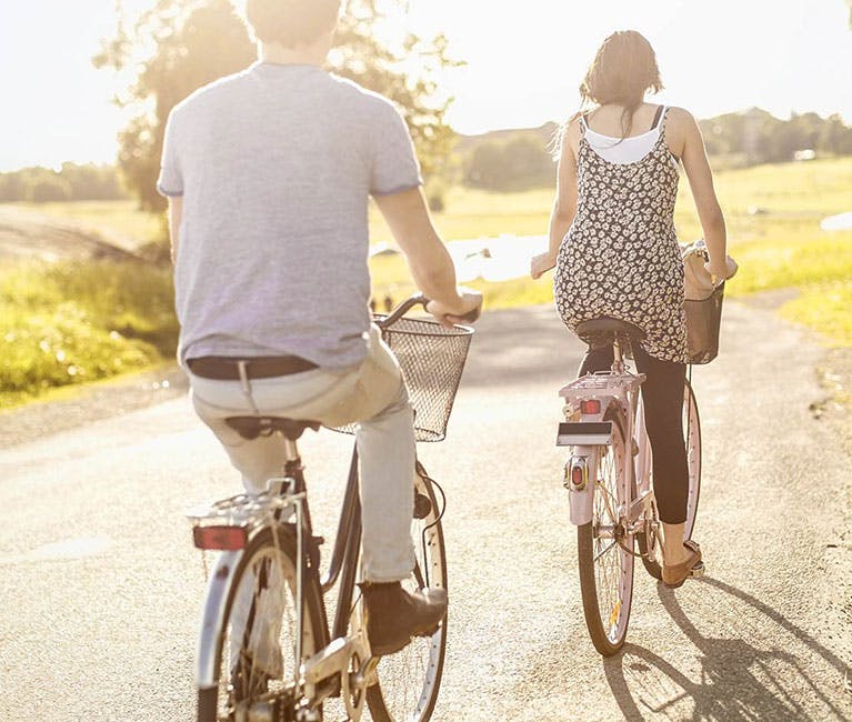 Couple riding bicycles in the countryside in summertime