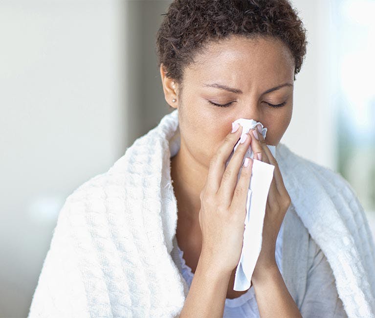 Woman dressed in winter clothing blowing her nose