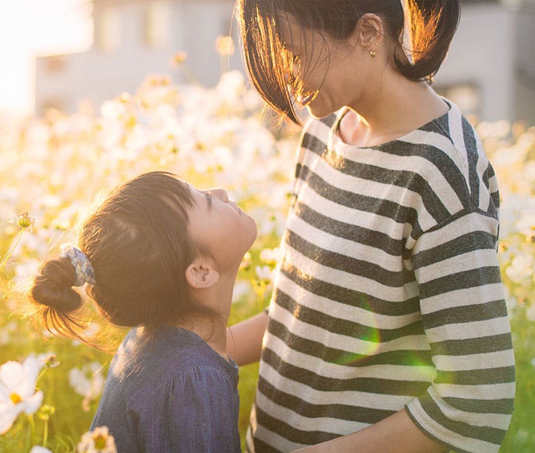 Femme dans une prairie ensoleillée jouant avec une petite fille.