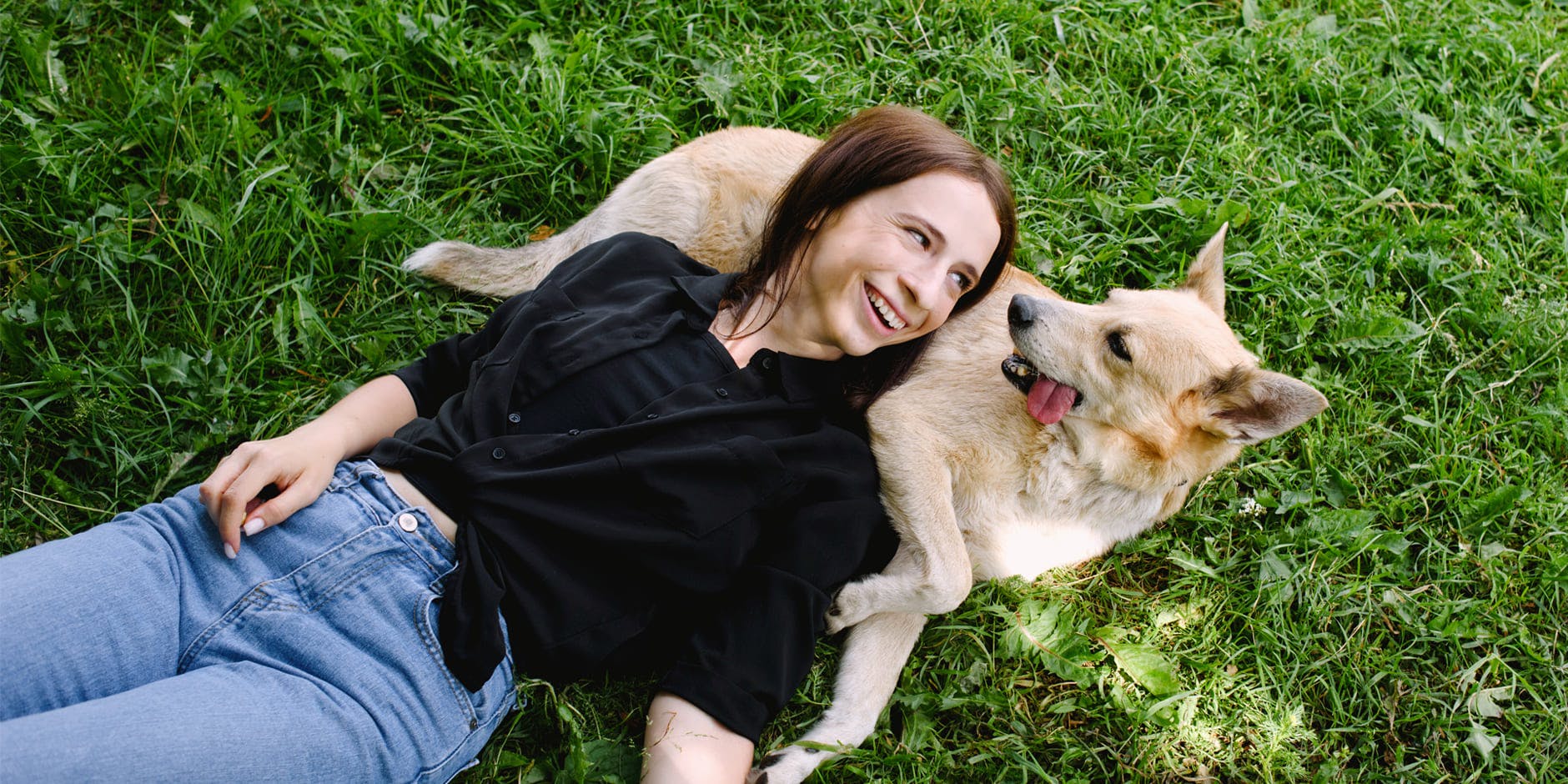 Nő mosolyogva fekszik a kutyáján