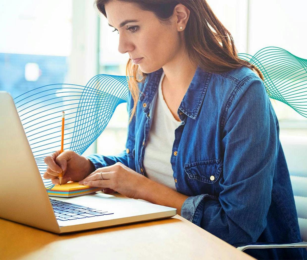 Színhely irodai környezetben, nő ül a laptopnál és jegyzetel
