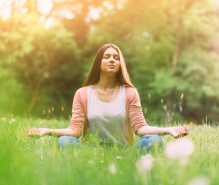Tips til deg som er plaget av pollenallergi Ung kvinne i meditasjonsstilling i en grønn eng.