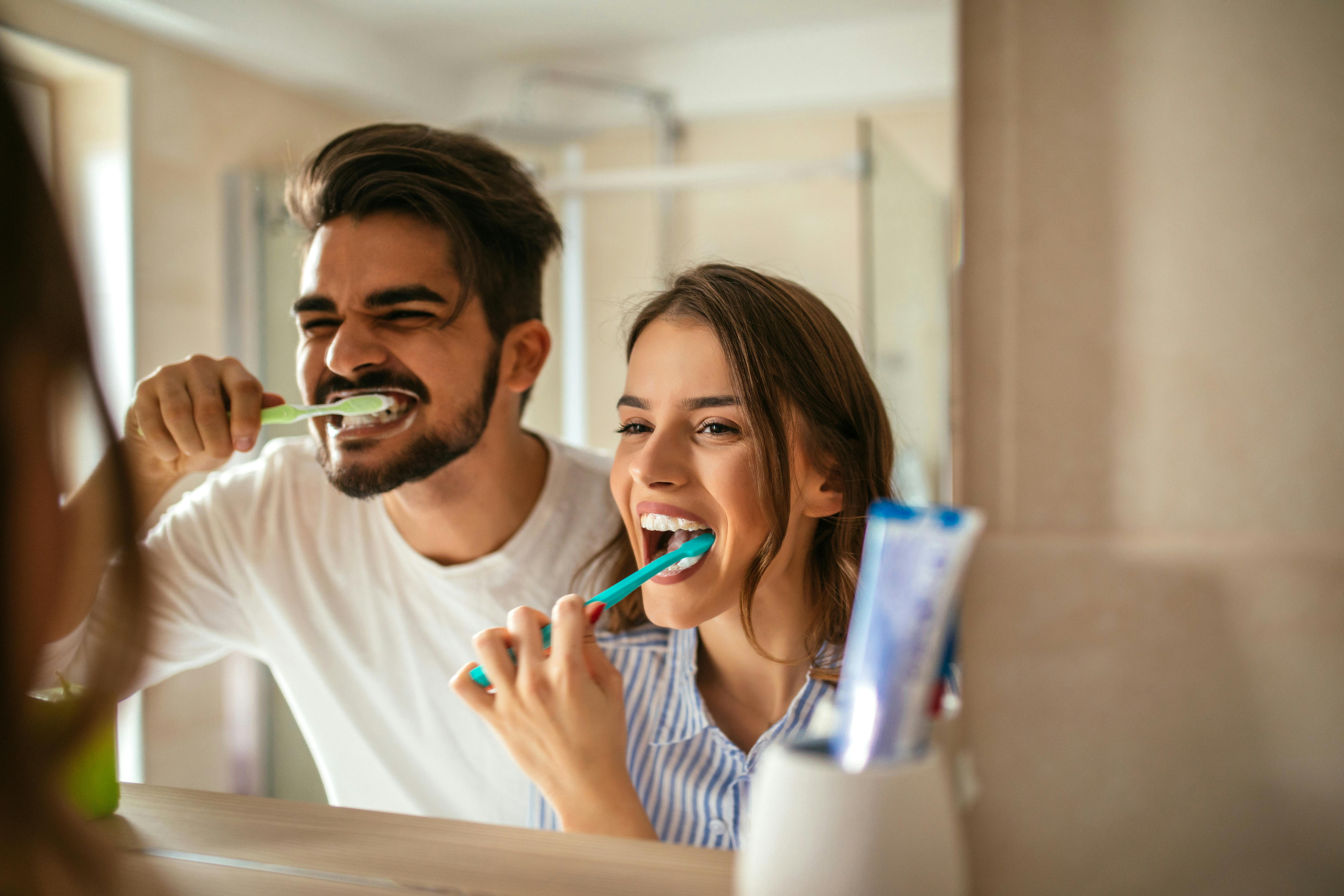 Man and woman brushing teeth in front of a mirror
