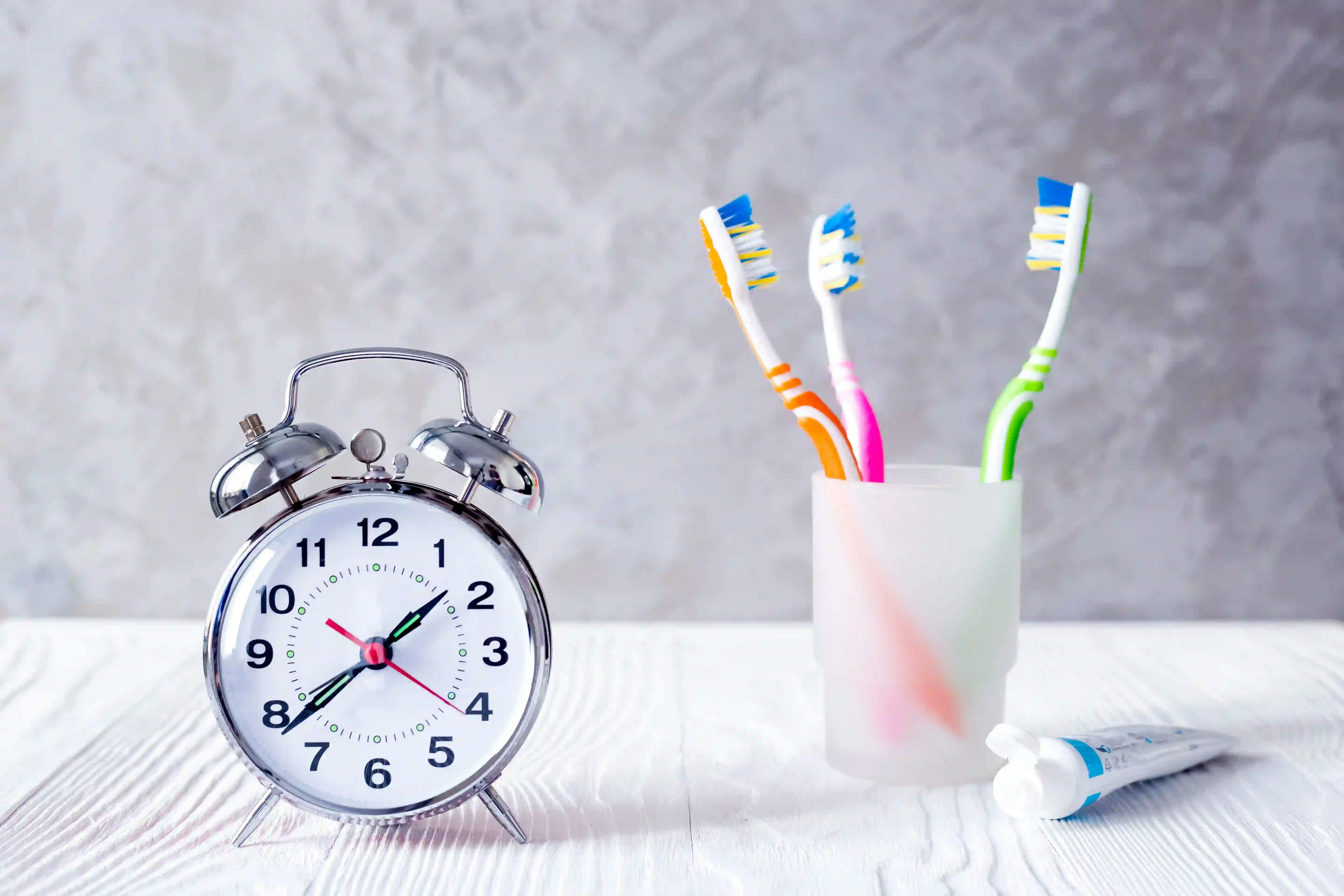 A clock and cup with toothbrushes