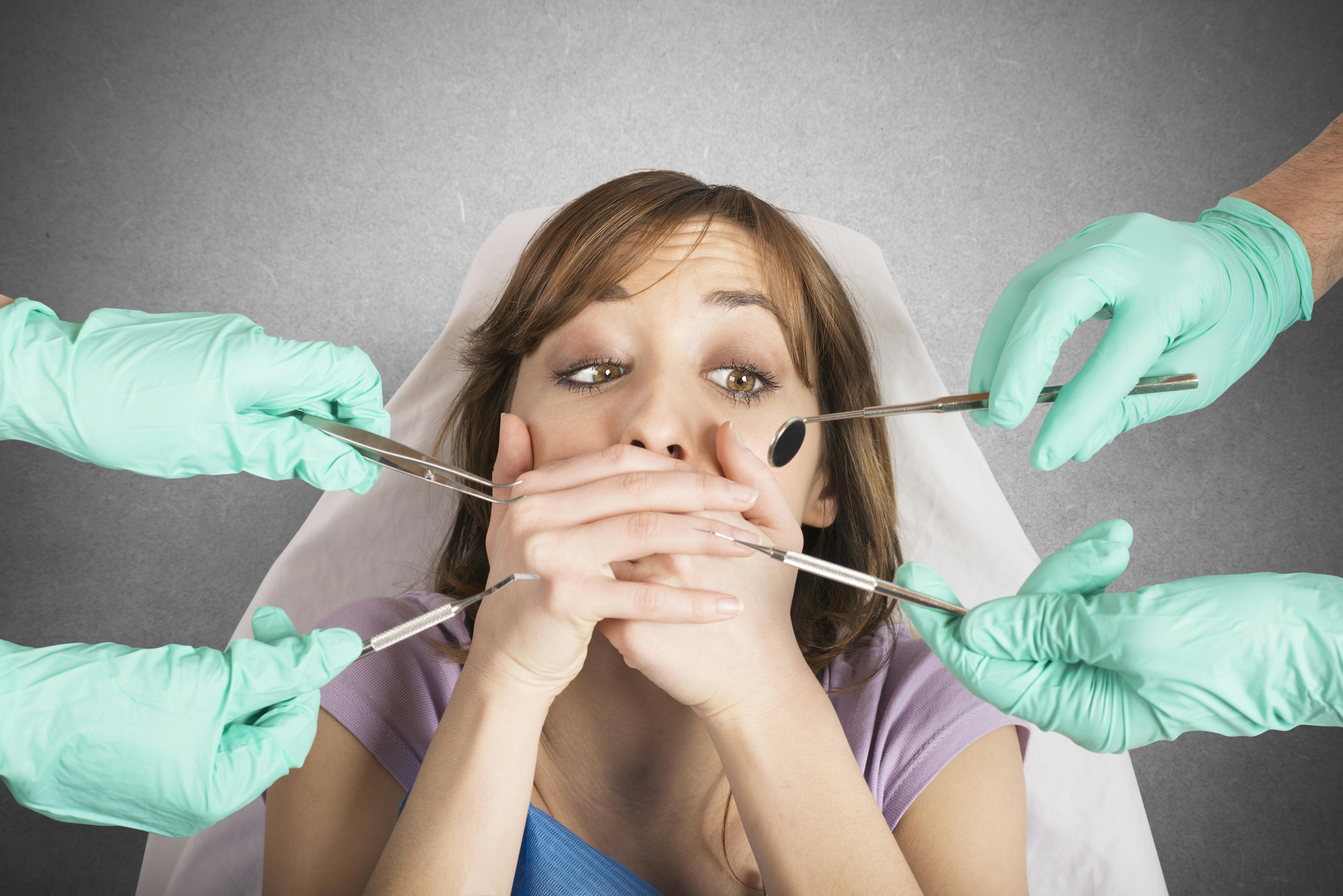 Girl covers her mouth with her hands while in a dental chair