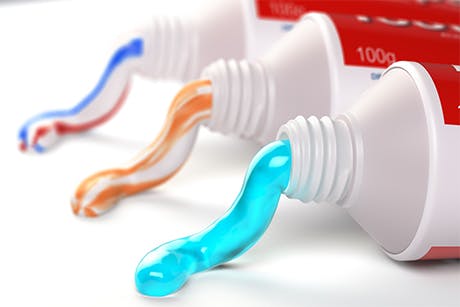 Three tubes with toothpaste coming out them