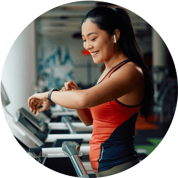 Smiling woman on a treadmill checks her smart watch