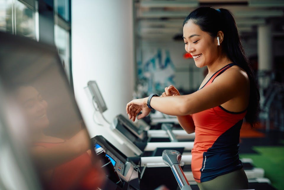 Smiling woman on a treadmill checks her smart watch