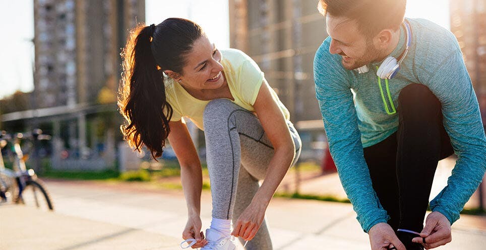 Man and woman in running gear tying shoe laces Man and woman in running gear tying shoe laces