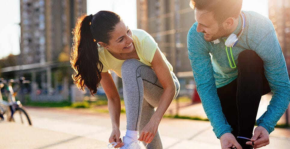 Man and woman in running gear tying shoe laces