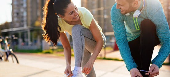 Man and woman in running gear tying shoe laces Man and woman in running gear tying shoe laces