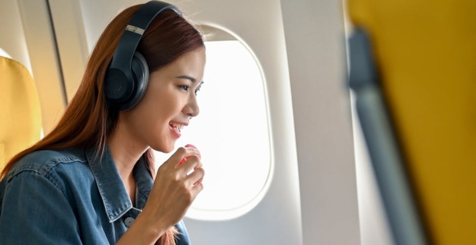 Woman eating a snack while surfing on the computer in a commercial airplane 