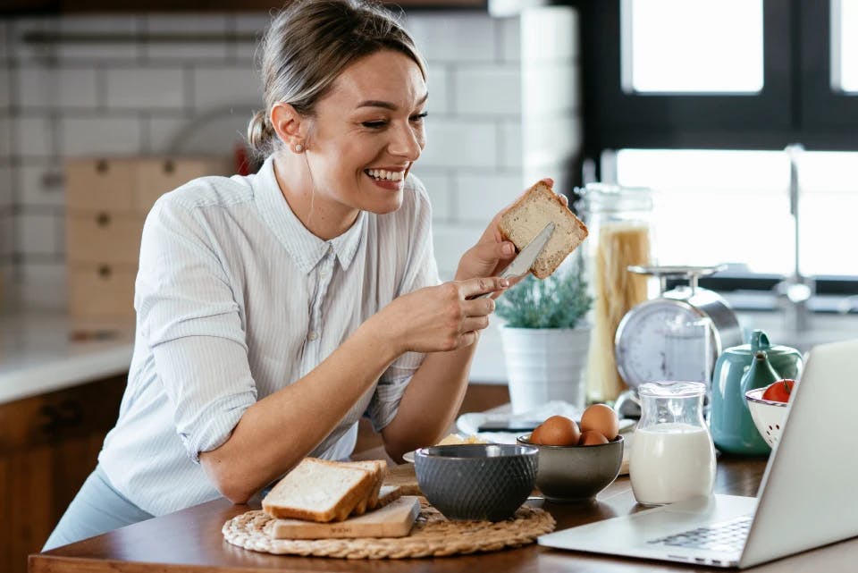 Smiling woman eating toast in kitchen