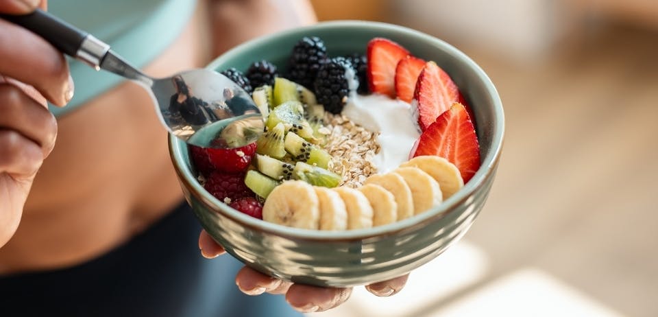 Woman eating a bowl of fruit and oatmeal