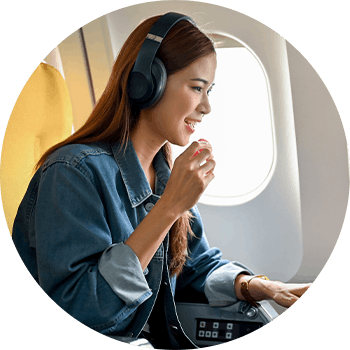 Woman eating a snack while surfing on the computer in a commercial airplane 