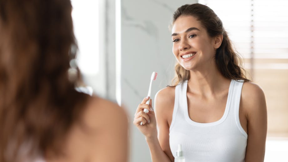 Woman holding toothbrush in front of mirror