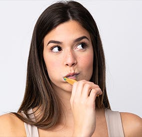 Woman brushes teeth while looking sideways 