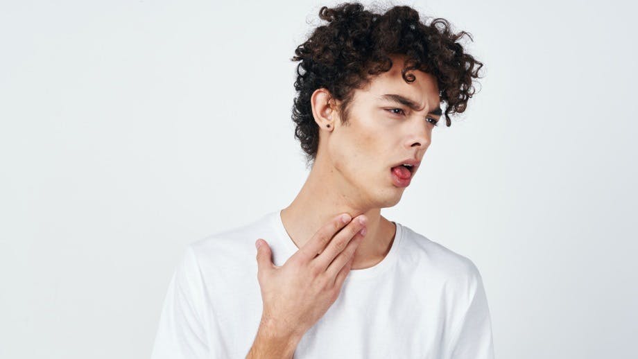 A man coughing while touching his throat. A man coughing while touching his throat.