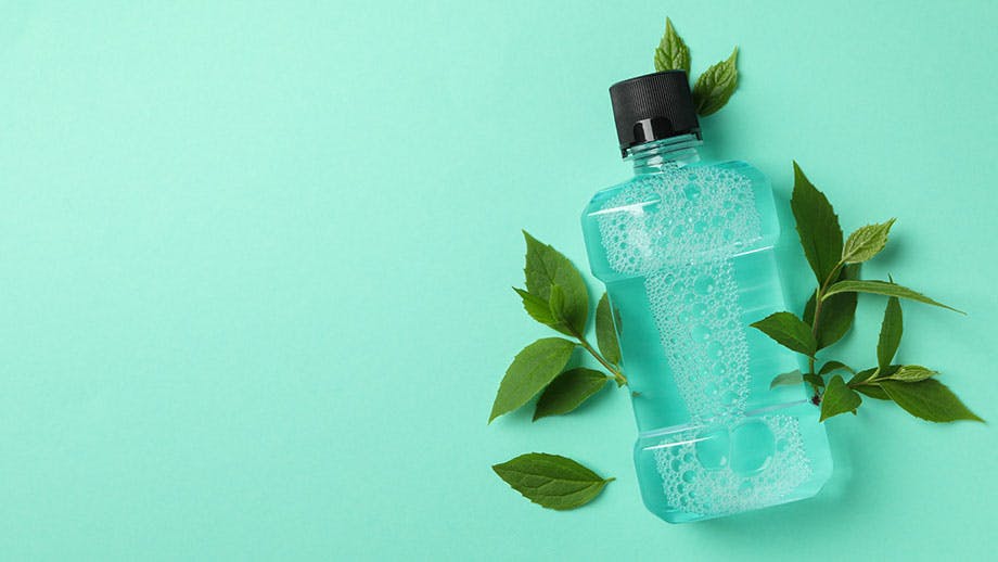 close-up of hands pouring mouthwash from mouthwash bottle into cap