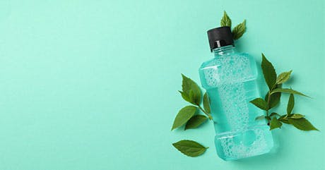 close-up of hands pouring mouthwash from mouthwash bottle into cap