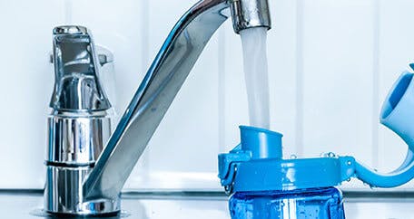 Bottle being filled with water from kitchen sink