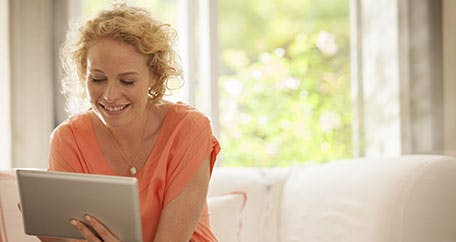 Women using an iPad while sitting on a couch