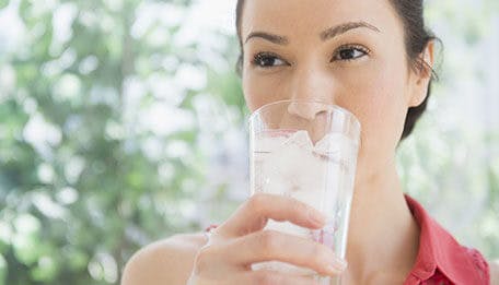 woman drinking a glass of iced water