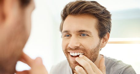 Man looking at mouth in mirror