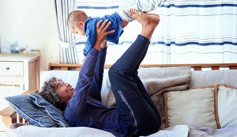 Person lying on back lifting a baby in the air