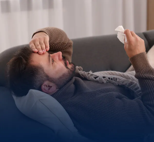 Man reclining on a couch and holding head in pain