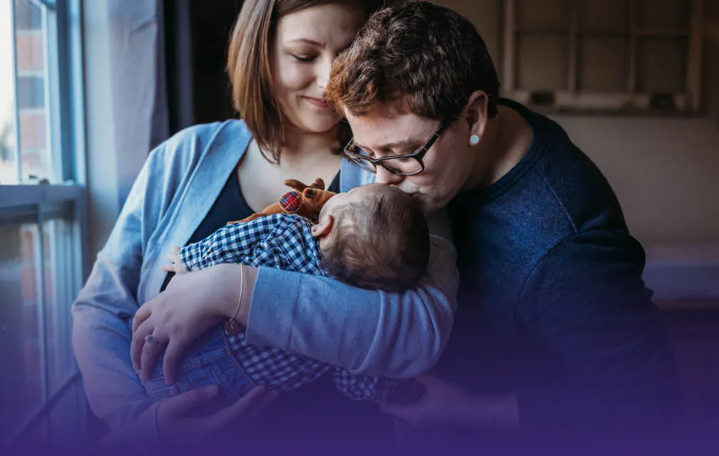 Family kissing an infant