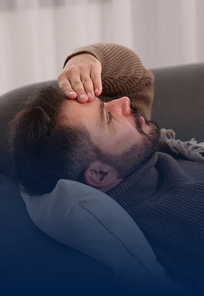 Man reclining on a couch and holding head in pain