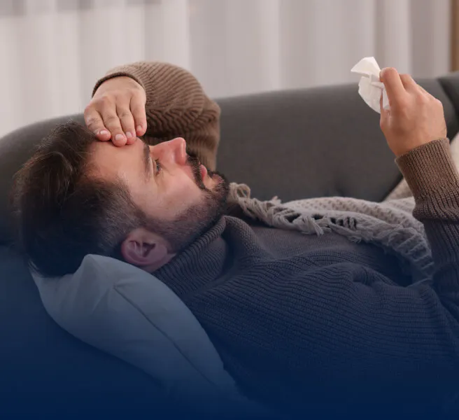 Man reclining on a couch and holding head in pain