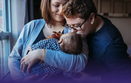 Family kissing an infant