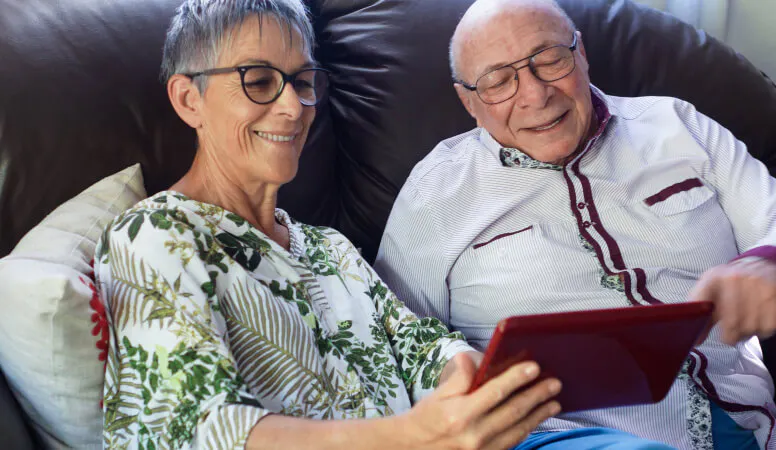 An elderly couple looking at a tablet 
