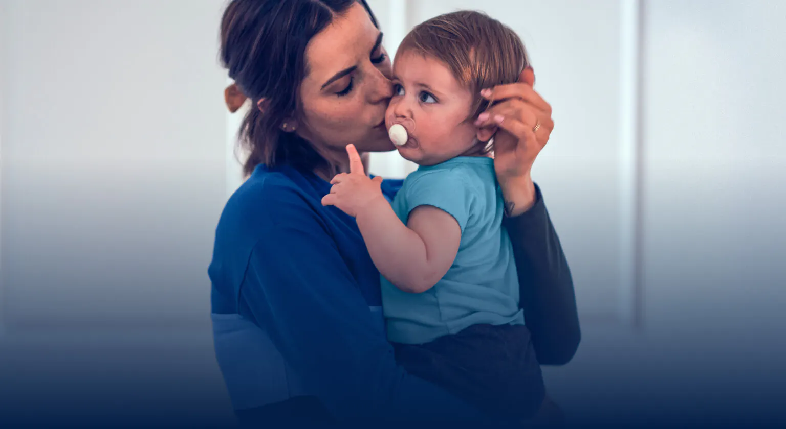 Mother holding and kissing a baby