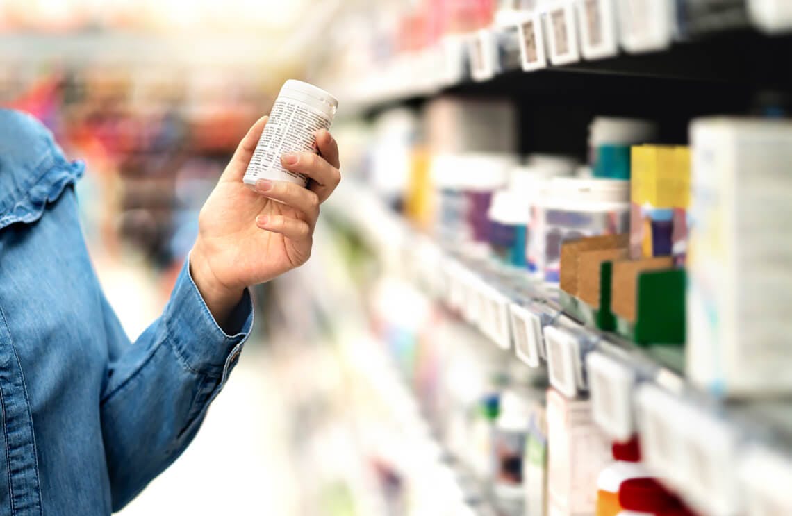 Person reading medicine label in a store aisle