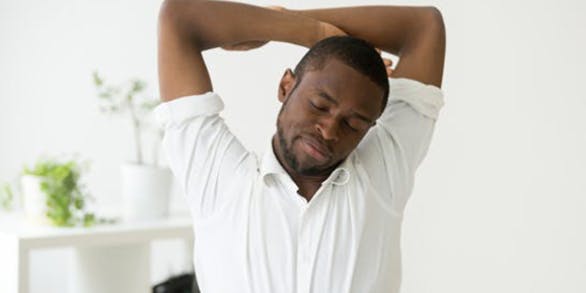 African american man stretching doing easy office exercises to relieve muscle tension from sedentary work
