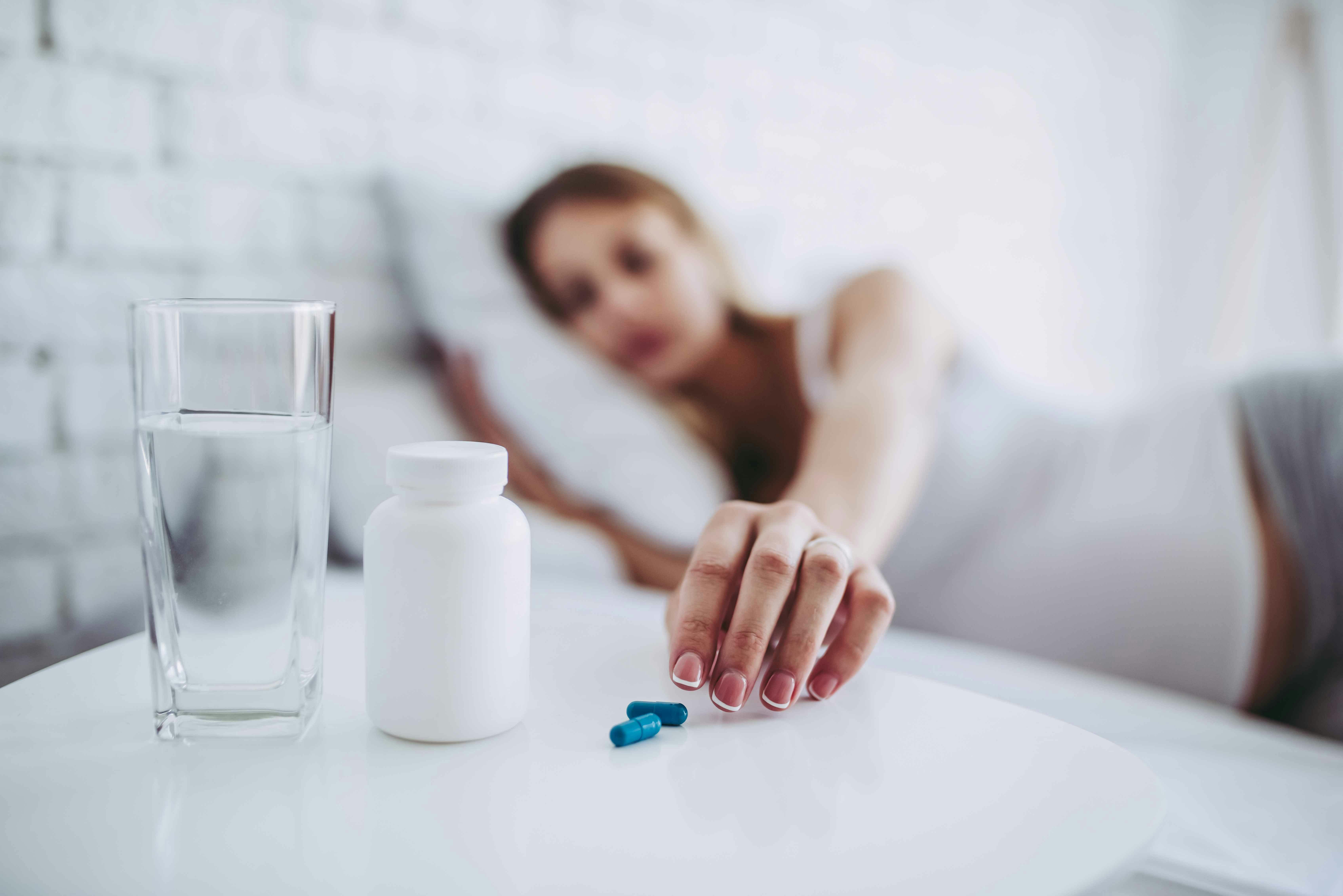 Woman taking pills in bed Woman taking pills in bed