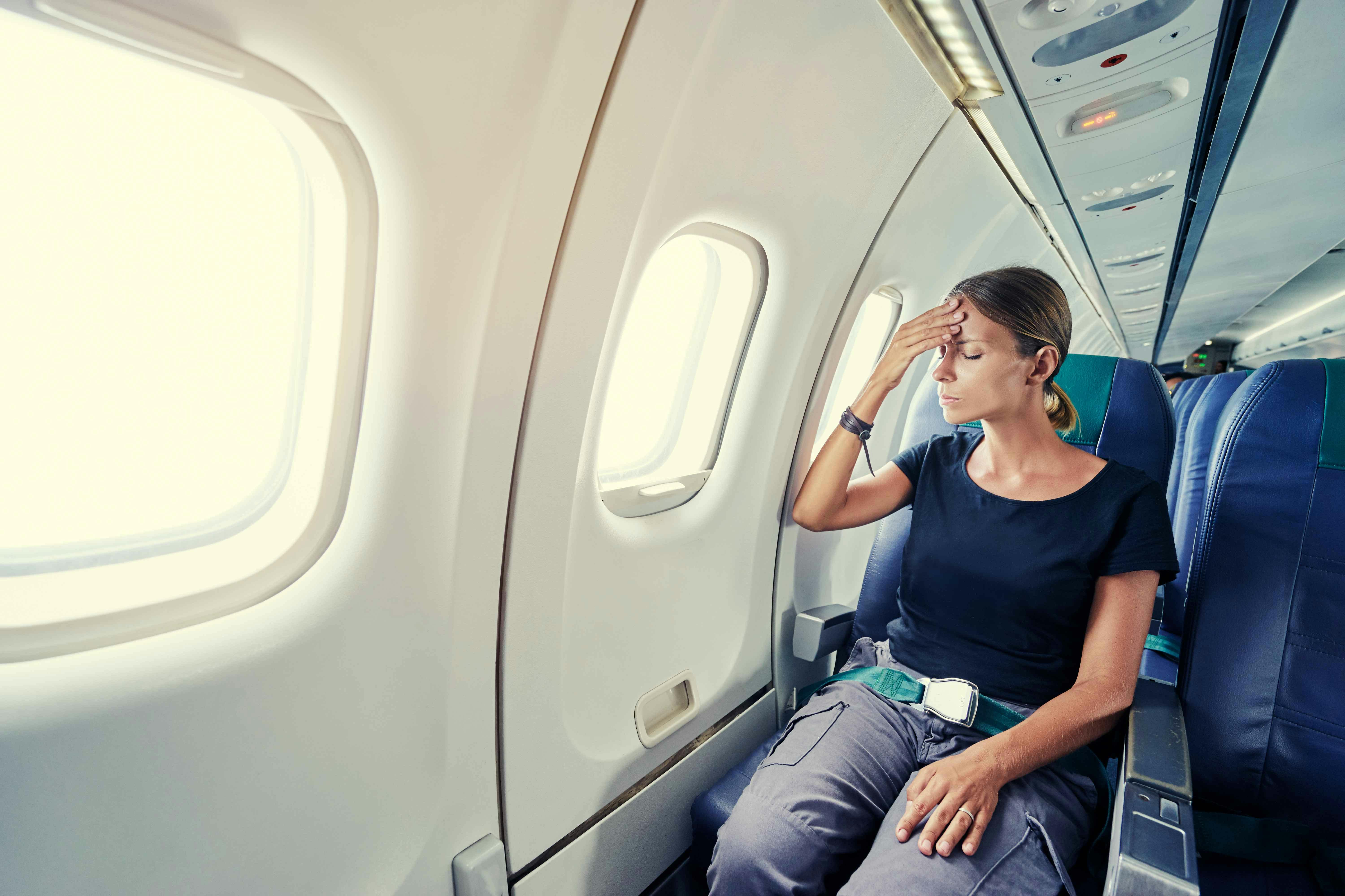 Woman suffering from headache on airplane