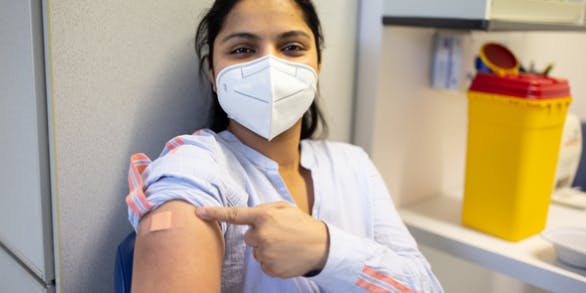 A young woman showing COVID-19 Vaccine mark in hand