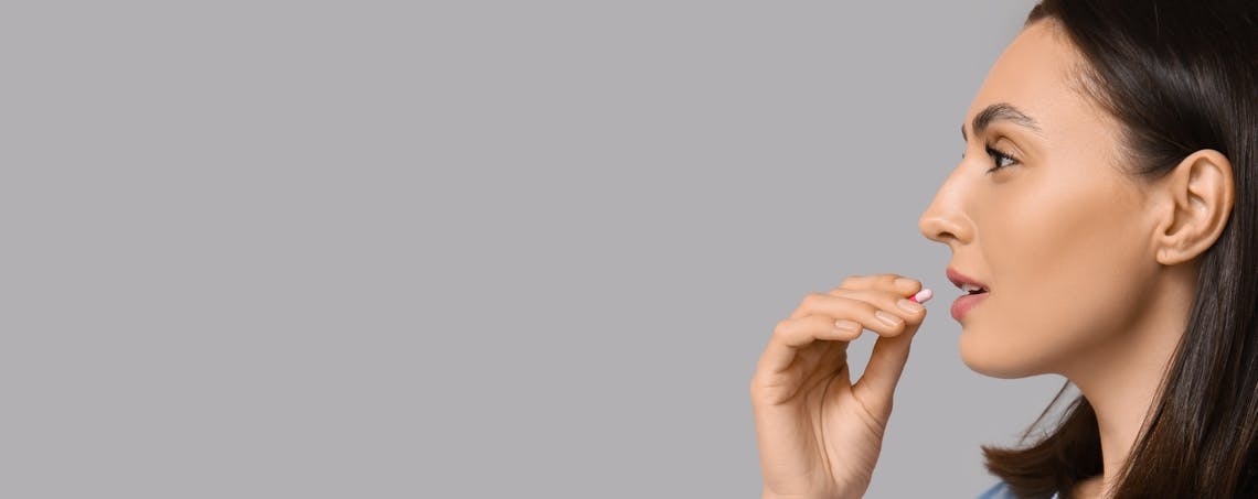 Woman taking a pill with a glass of water