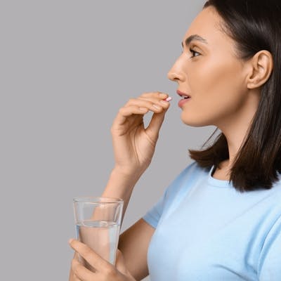 Woman taking a pill with a glass of water