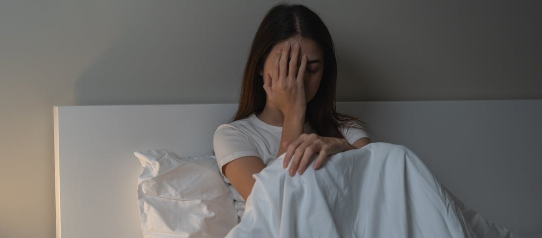 Woman sitting up in bed unable to sleep