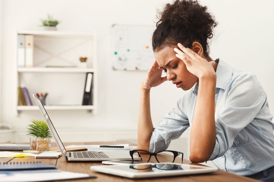 Young woman at desk with a headache.