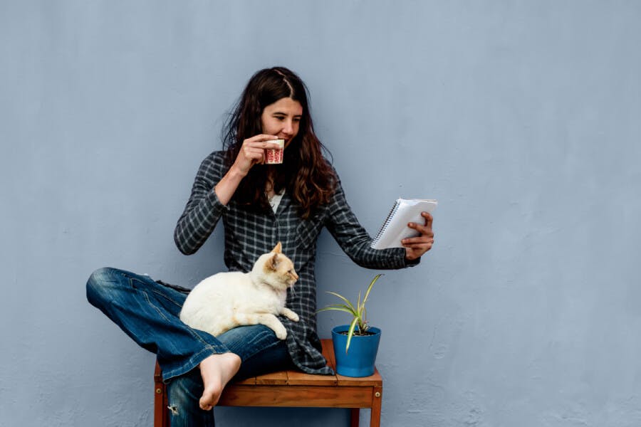 Woman reading notebook with a cat on her lap 