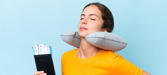 A woman holding her passport and plane tickets with her other hand on her lumbar area A woman holding her passport and plane tickets with her other hand on her lumbar area